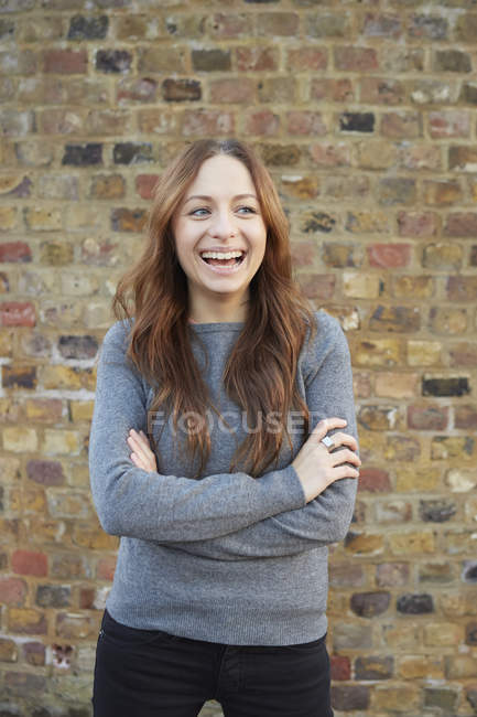 Porträt einer jungen Frau, im Freien, die Arme verschränkt, lachend — Stockfoto