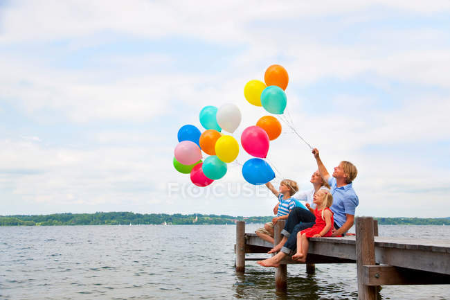 Família segurando balões no cais de madeira — Fotografia de Stock