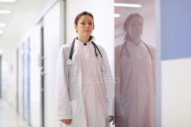 Portrait of young female doctor standing in hospital corridor — Stock Photo