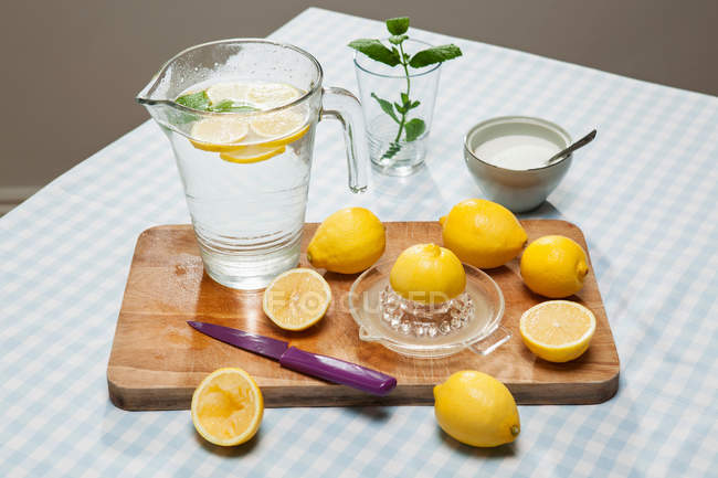 Limones con exprimidor sobre tabla de madera - foto de stock