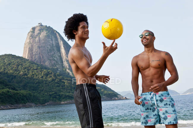Dos amigos en la playa con voleibol, Río de Janeiro, Brasil - foto de stock
