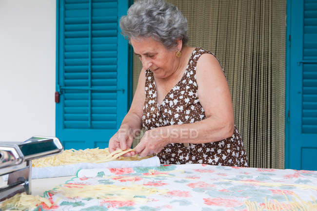 Older woman making pasta with roller — Stock Photo