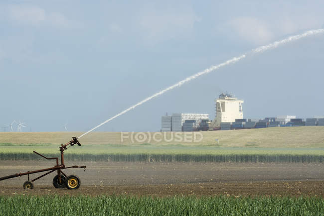 Irrigation des cultures en raison d'une sécheresse prolongée. Un porte-conteneurs quittant le port d'Anvers en arrière-plan, Rilland, Zélande, Pays-Bas — Photo de stock