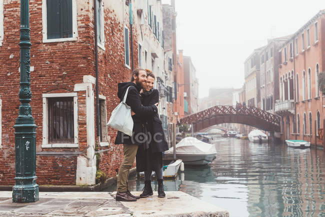 Coppia abbracci sul lungomare del canale nebbioso, Venezia, Italia — Foto stock