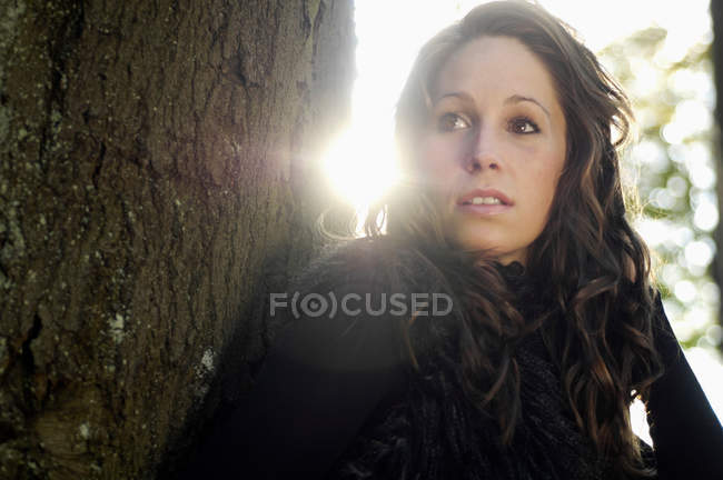 Retrato de jovem mulher por tronco de árvore no outono — Fotografia de Stock
