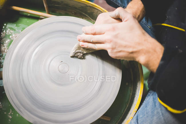 Overhead view of mid adult mans hands cleaning pottery wheel — Stock Photo