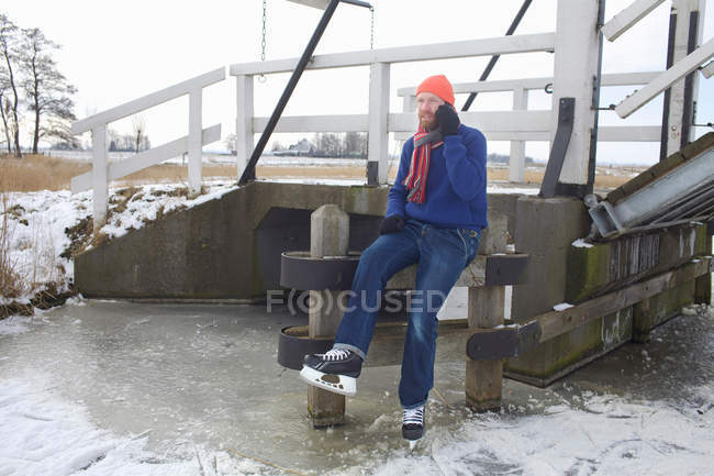 Man in ice skates talking on cell phone — Stock Photo