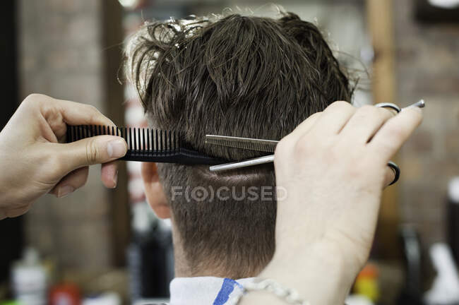 Вид спереду молодого чоловіка в перукарні, який стрижеться — стокове фото