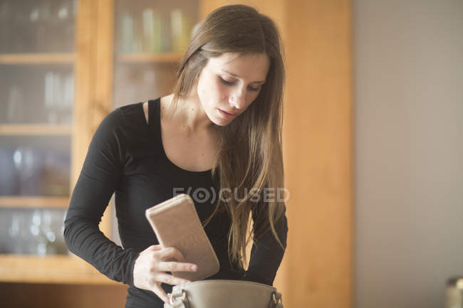 Jovem mulher em casa, olhando através de bolsa — Fotografia de Stock