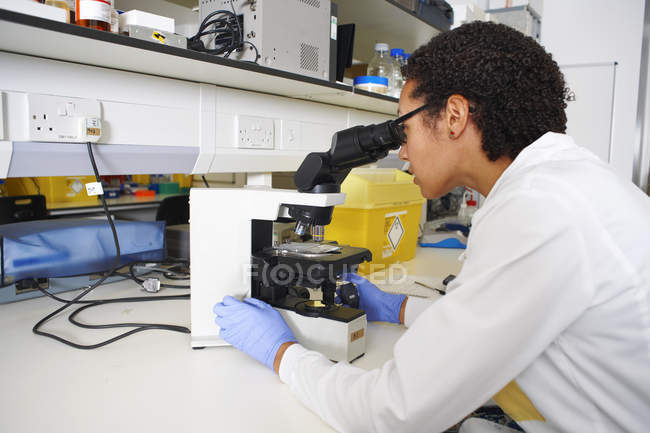 Cientista feminina olhando através do microscópio — Fotografia de Stock