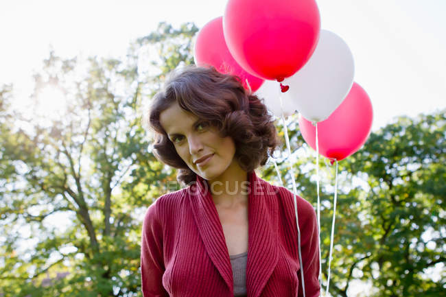 Mujer llevando globos al aire libre, se centran en primer plano - foto de stock