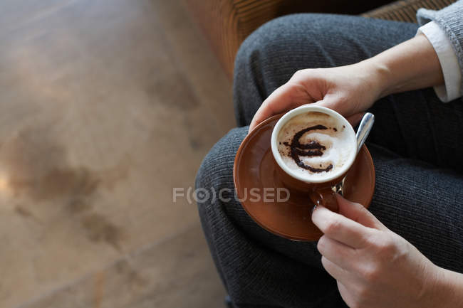 Woman holding cappuccino with euro motif — Stock Photo