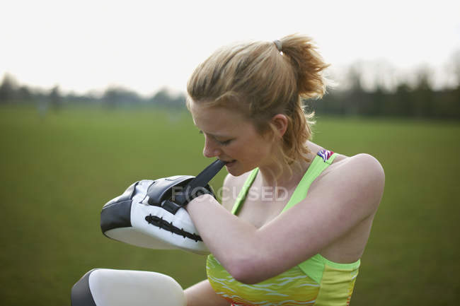 Portrait of a woman putting on boxing pads in the park — Stock Photo
