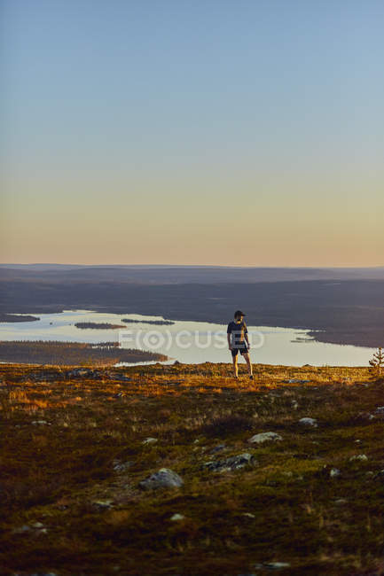 Homme se reposant après avoir couru au sommet de la falaise au coucher du soleil, Keimiotunturi, Laponie, Finlande — Photo de stock
