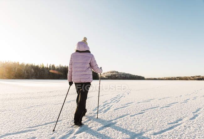 Woman nordic walking through snow covered field — Stock Photo
