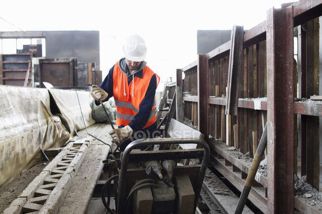 Работник завода выбирает стальной стержень на бетонном заводе — стоковое фото