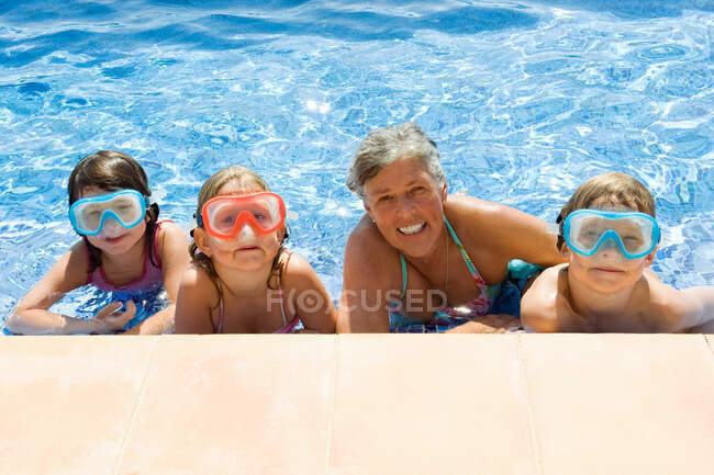Children with a senior female in a pool — Stock Photo