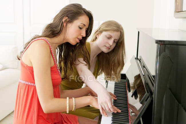 Teenage girls playing piano together — Stock Photo