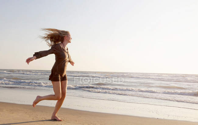 Mature woman running along beach — Stock Photo