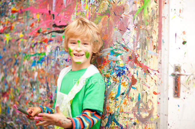 Garçon devant un mur éclaboussé de peinture — Photo de stock