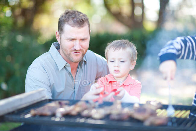 Padre e hijos haciendo barbacoas - foto de stock