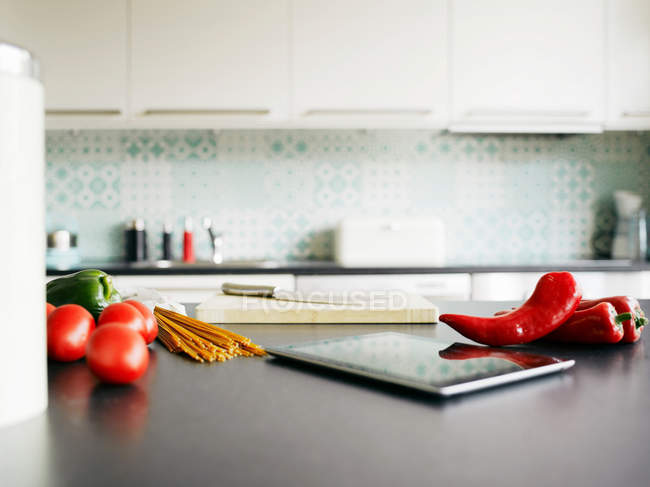 Tablet with peppers and tomatoes on counter — Stock Photo