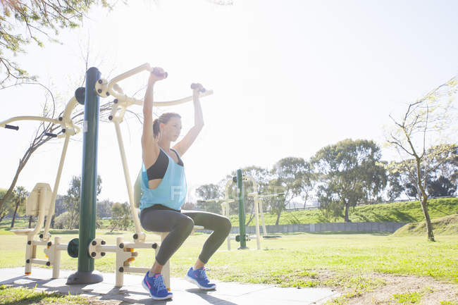 Mitte erwachsene Frau trainiert auf Rudergerät im Park — Stockfoto