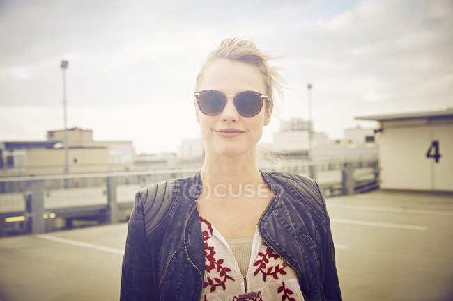 Retrato de mulher adulta média vestindo tons no estacionamento no telhado — Fotografia de Stock
