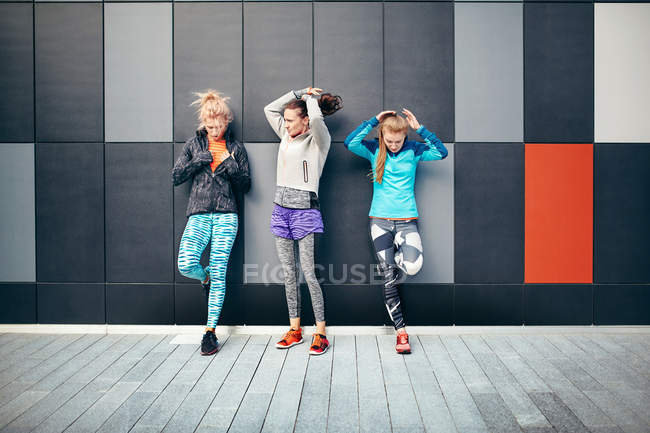 Three female runners putting up their hair in city underpass — Stock Photo