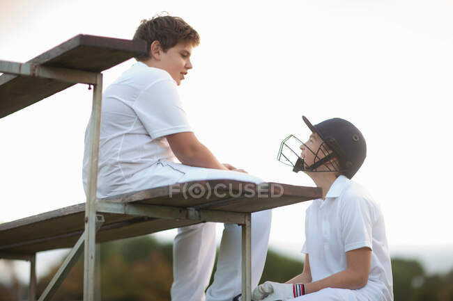Rapazes em bancadas no campo de críquete — Fotografia de Stock