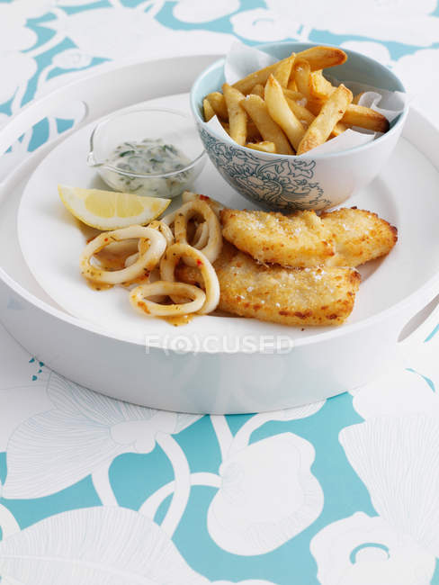 Ciotola di patatine con pesce e limone sul vassoio — Foto stock