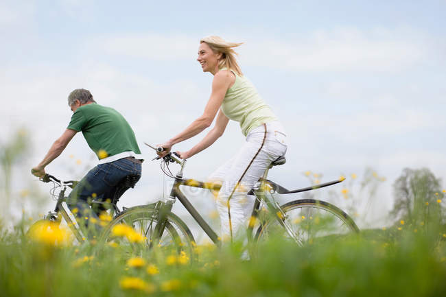 Пара їздять на велосипедах у полі — стокове фото