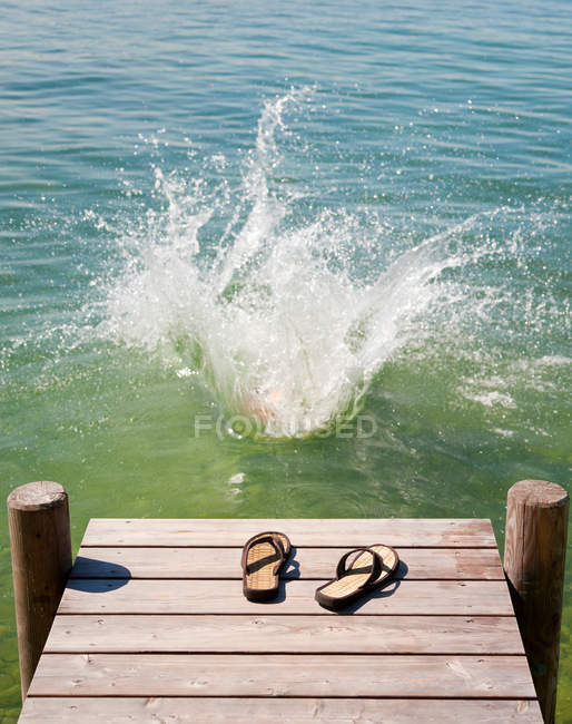 Фліп-флоп на дерев'яній палубі біля озера — стокове фото