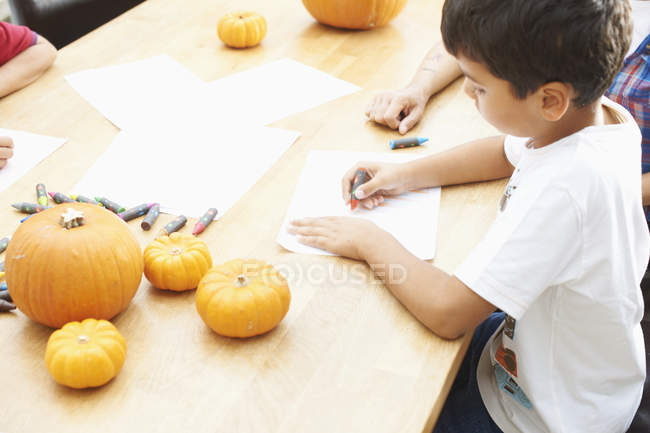 Hermanos dibujando en la mesa de comedor en casa - foto de stock