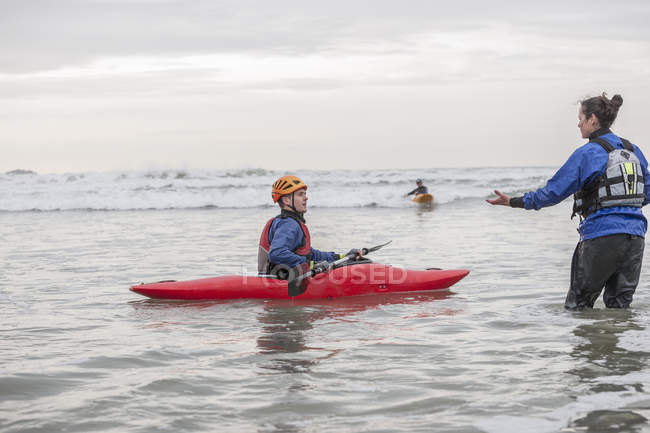 Female instructor helping young man in sea kayak — Stock Photo