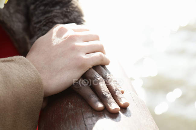 Couple multi ethnique à l'extérieur, homme se reposant la main sur la main de la femme, gros plan — Photo de stock