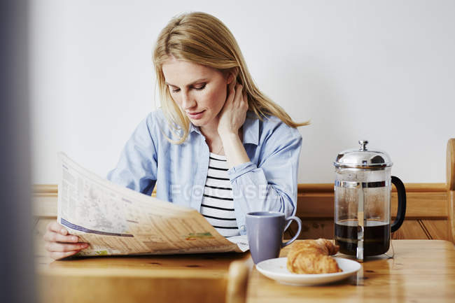 Mid adult woman reading newspaper — Stock Photo