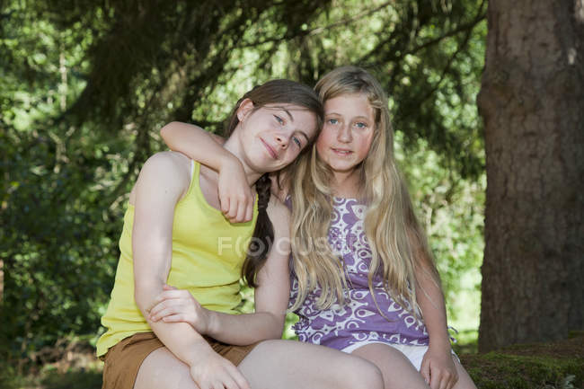 Подростки сидят в саду с обнимающимися руками — стоковое фото