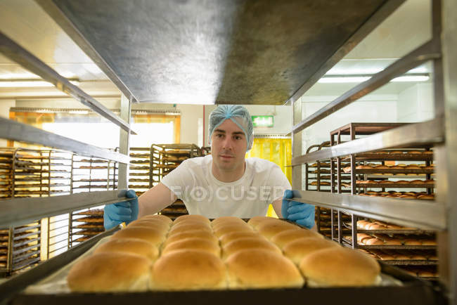 Baker organising trays of freshly baked bread — Stock Photo