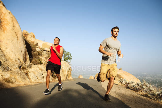 Dos amigos corriendo por el sendero de la montaña - foto de stock