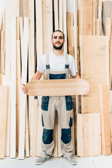 Hombre sosteniendo monopatín en taller - foto de stock