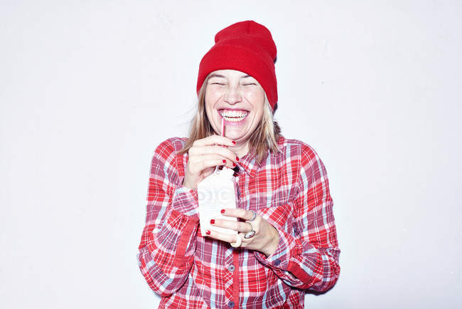 Молода жінка в червоному капелюсі п'є сік — стокове фото