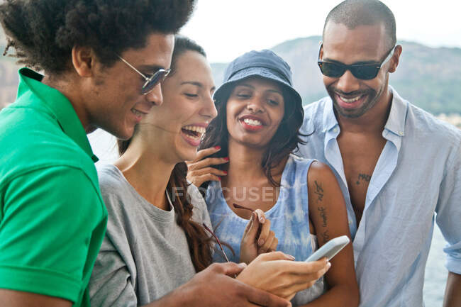 Четверо друзей смотрят на смартфон — стоковое фото