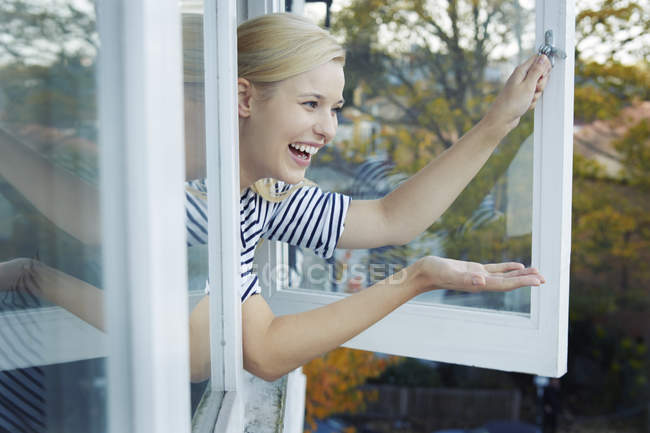 Young woman leaning out of window — Stock Photo