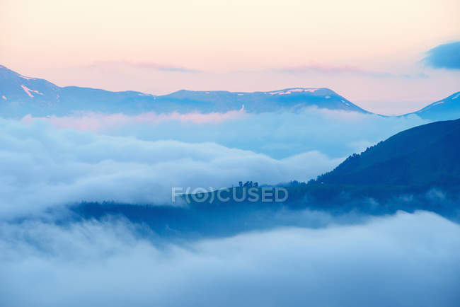 Vue sur les montagnes au-dessus des nuages au lever du soleil — Photo de stock