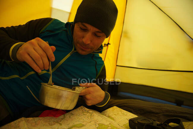 Homem comendo na barraca de acampamento — Fotografia de Stock