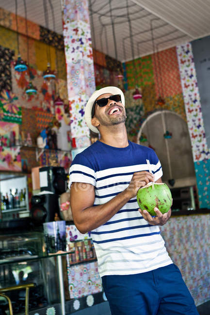 Чоловік тримає кокосовий напій і сміється — стокове фото