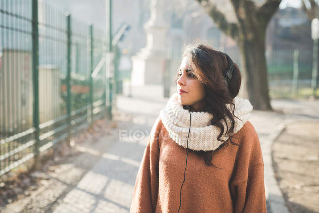 Jeune femme portant des écouteurs se promenant dans le parc — Photo de stock