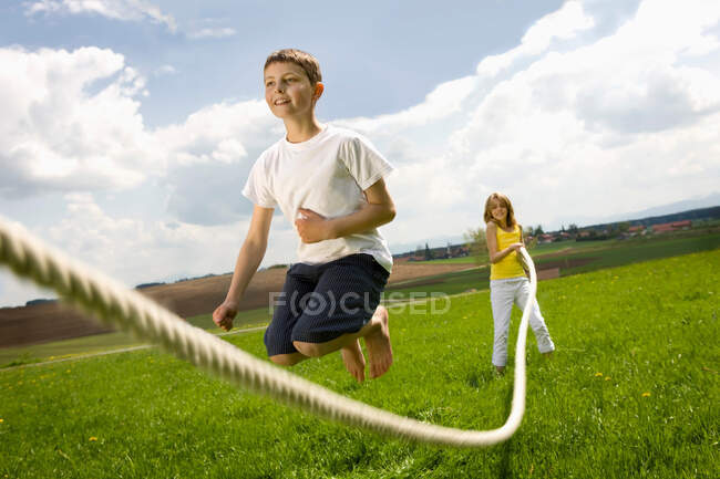 Crianças pulam de corda no campo — Fotografia de Stock