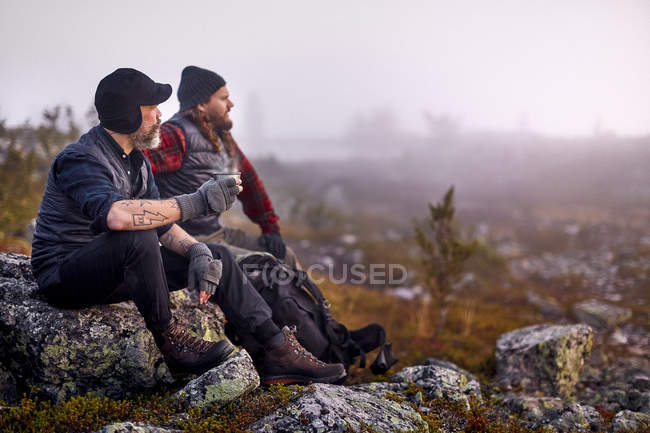 Randonneurs relaxants avec café sur terrain rocheux, Sarkitunturi, Laponie, Finlande — Photo de stock